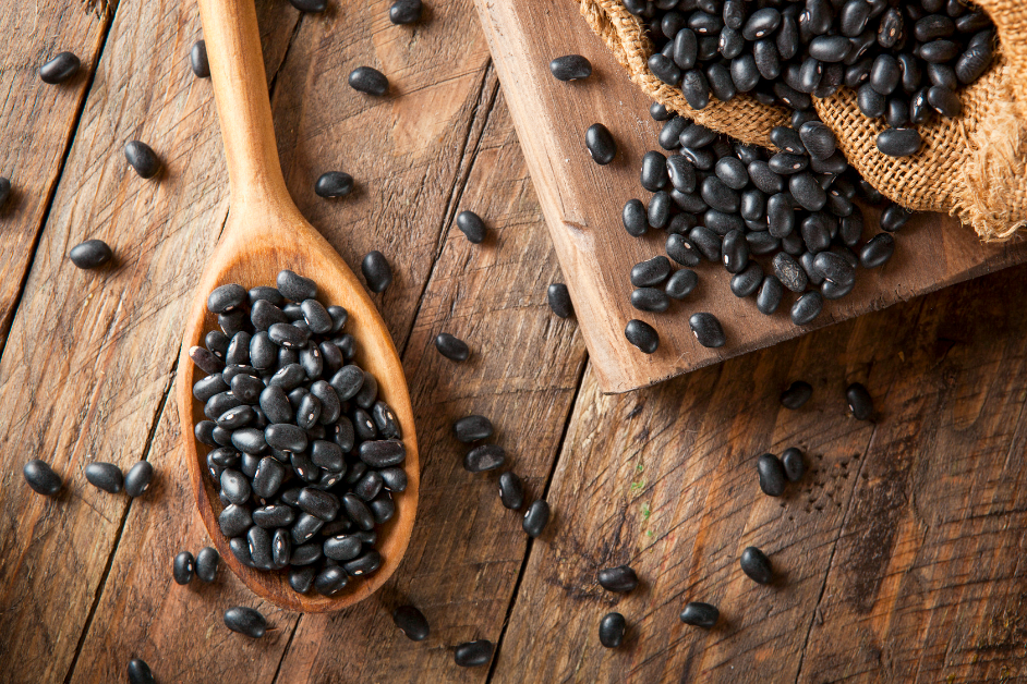 Black beans on a wooden cutting board, wooden table, and wooden spoon