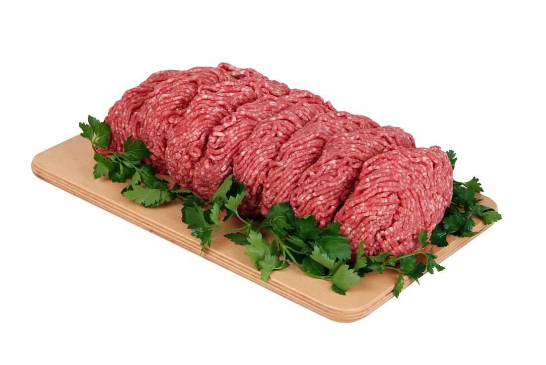 Ground beef on a wooden board with greens