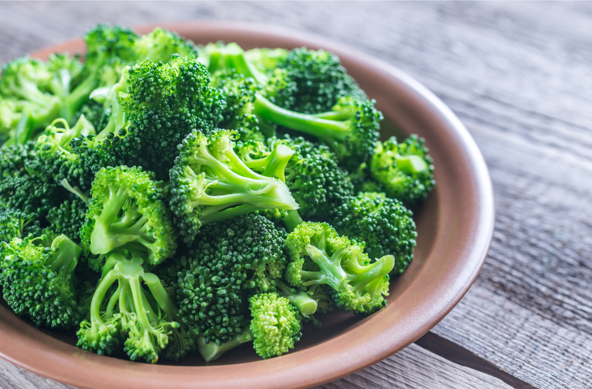 Broccoli florets in a brown bowl on a wooden table